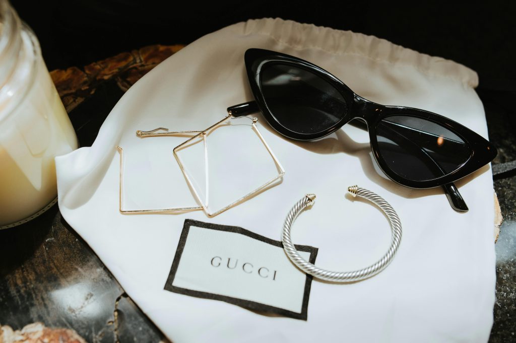 A stylish collection of luxury Gucci accessories including sunglasses, earrings, and a bracelet.